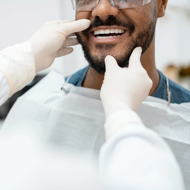 Dentist examining patient's teeth during clinical oral examination in dental office.